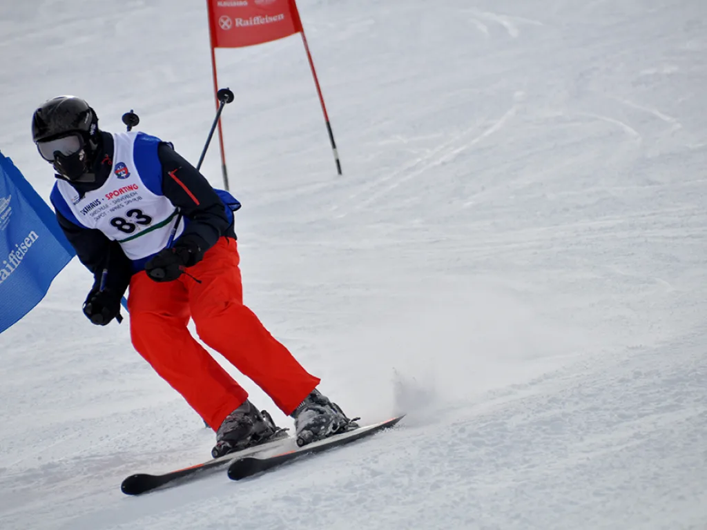 Skifahrer mit Startnummer 83 in tiefer Hocke am Tor.